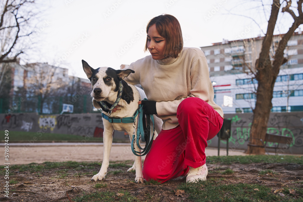 Caucasian woman hugging her dog on a walk in the park.