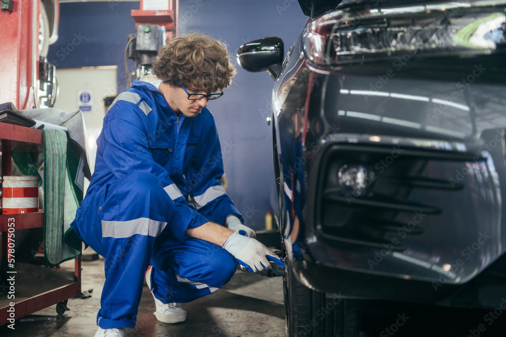 Automotive mechanic worker checking at car tyre rubber condition needed for replacement. after service at auto repair shop concept Automotive mechanic worker checking at car tyre rubber condition needed for replacement. after service at auto repair shop concept