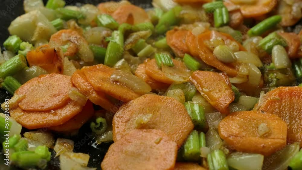 Super close-up of potato cubes falling on the vegetables roasting on the pan Super close-up of potato cubes falling on the vegetables roasting on the pan