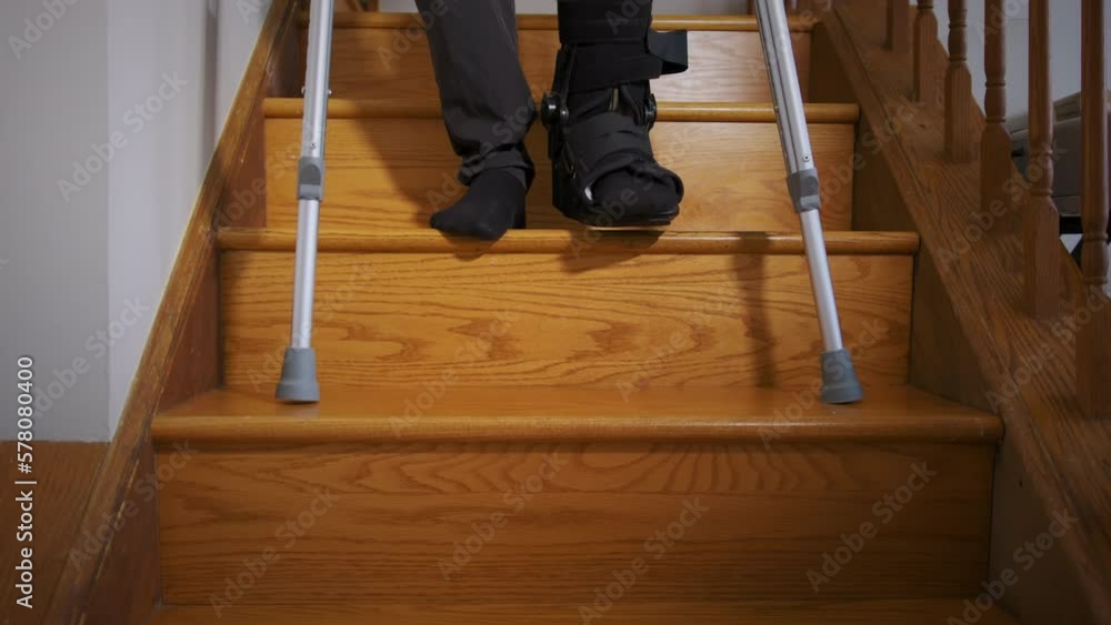 A man with broken leg in black Fracture Boot cast trying to walk with