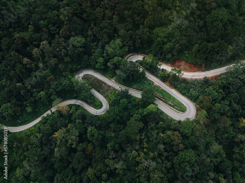 Aerial view of countryside road passing through the green forrest and mountain photo