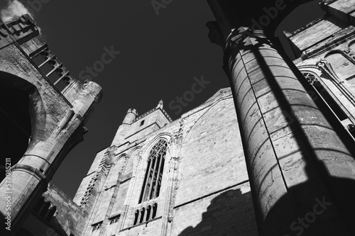 Cathedral of Saints Justus and Pastor in Narbonne, France. Church tower seen through unfinished part of the building in sunset light.  A game of light and shadow on column. Black white historic photo photo