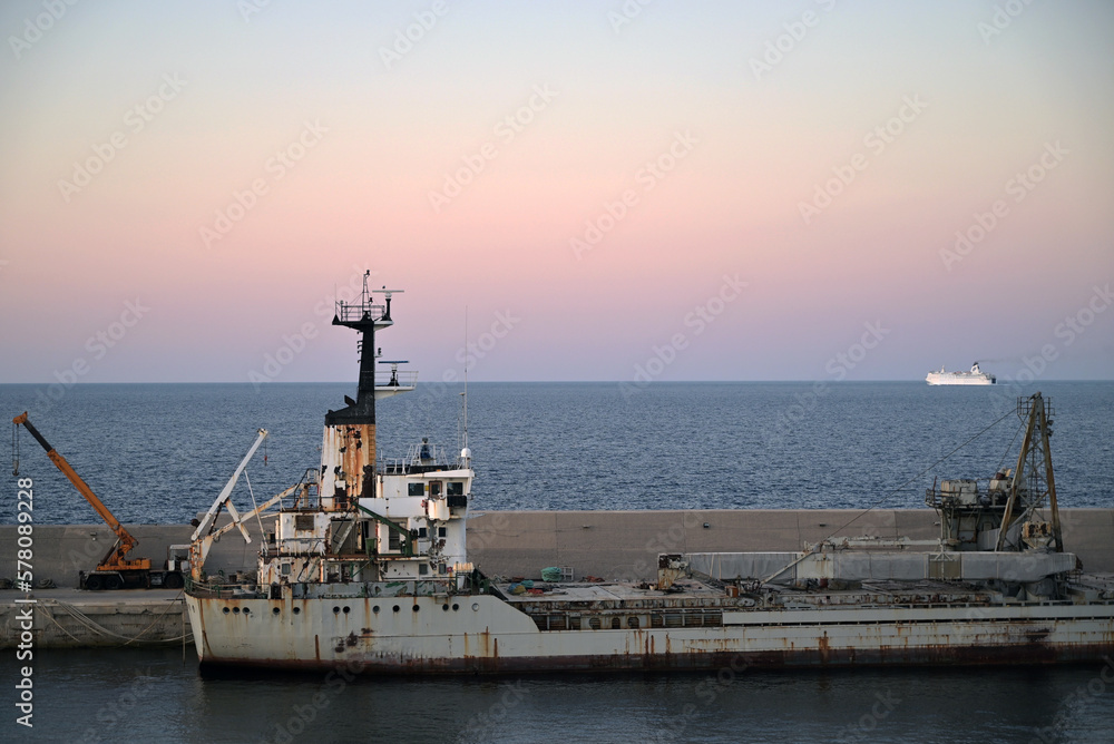 Old merchant ship moored in port. End of day sunset. Old merchant ship moored in port. End of day sunset.