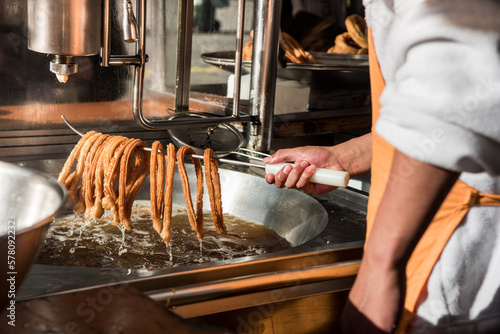 Detail photo of a worker removing the churros from the hot oil, ready to be served in the street.
