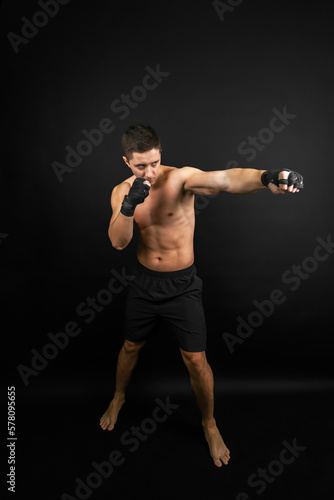 Boxer throwing a punch. Photo of muscular man isolated on black background. Strength and motivation. © Georgi