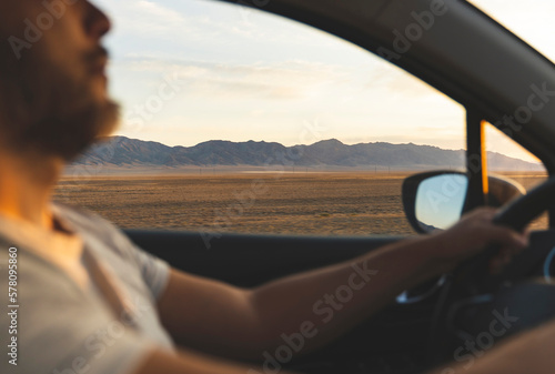 Man driving a car. Beautiful nature and mountains at sunset in side window. © tache