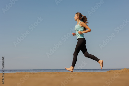 jogging, sporty woman runs in morning on seashore. fitness millennial female trains for marathon, healthy lifestyle, love for her body, mental and physical condition, sportswear, champion