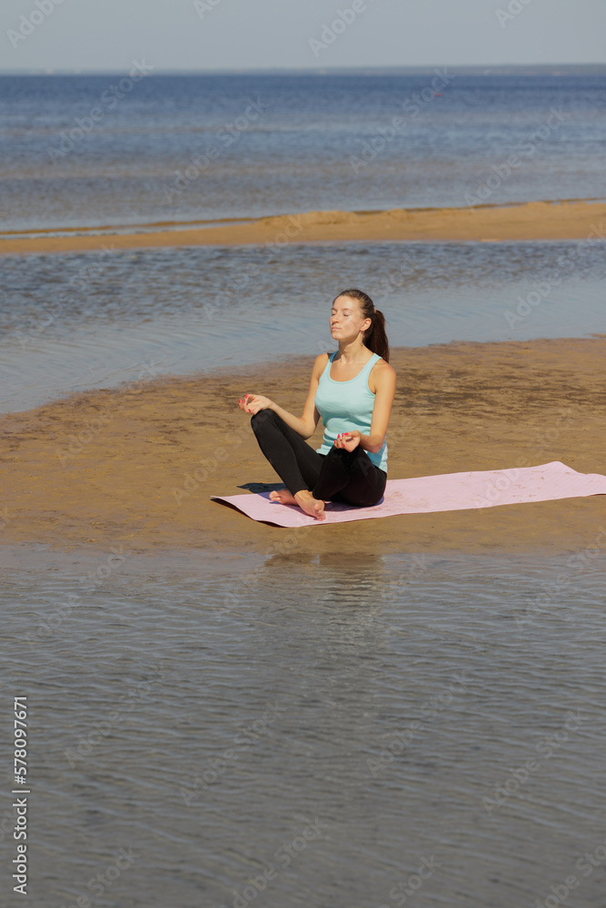 Fototapeta premium yoga, woman do meditation on seashore in morning. fitness millennial female trains, asana breathing practice hands in namaste, lotus pose, healthy lifestyle, love your body, mental physical condition