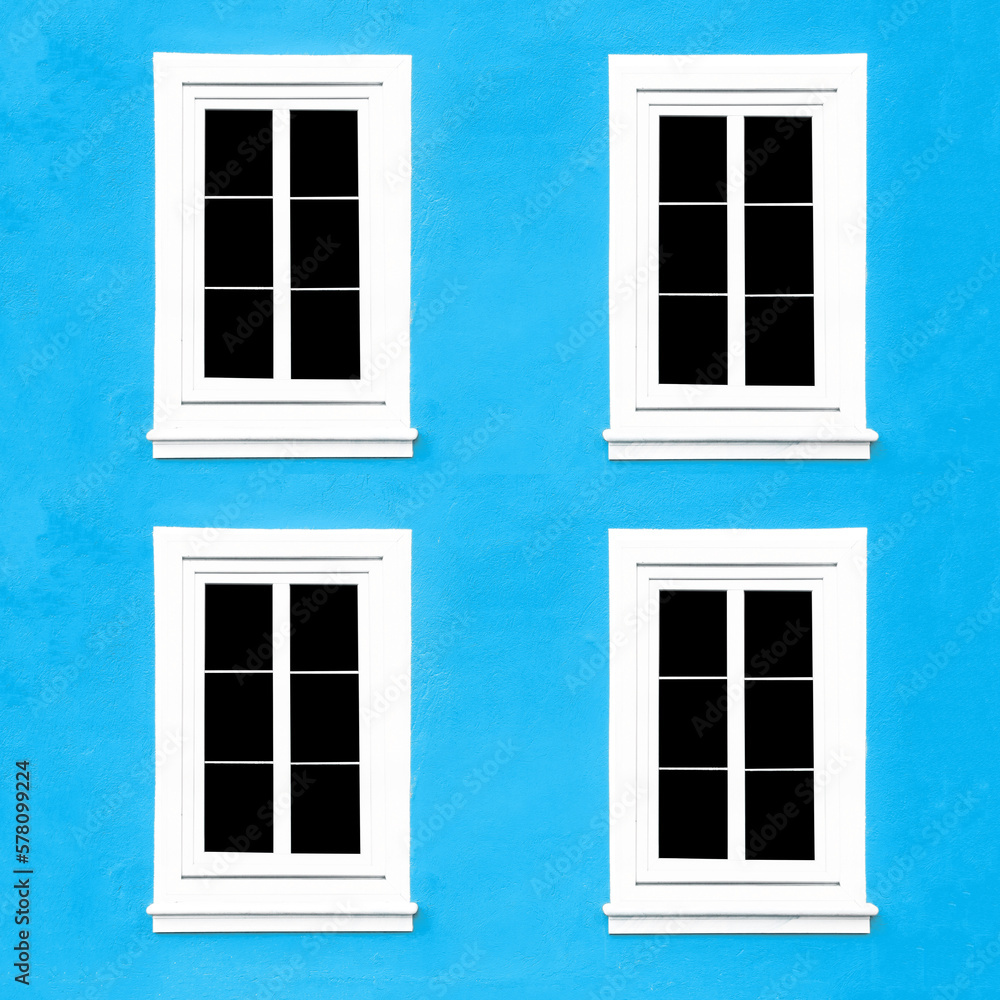 PVC Windows. Architecture background. Vibrant color blue wall facade. Small town house exterior. Street of European city building. Four window frames isolated on empty wall. Simple windows in a row.