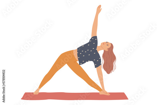 Woman performs yoga exercises by bending to the side and raising her hand - a triangle pose, three corners or Trikonasana.
