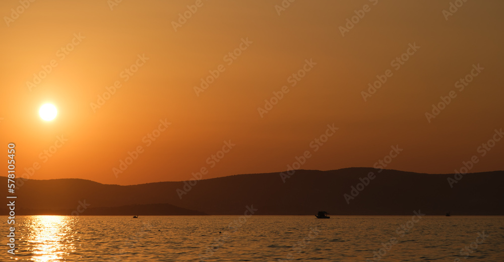Sunset landscape with fishing boat on distant background.