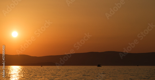 Sunset landscape with fishing boat on distant background.