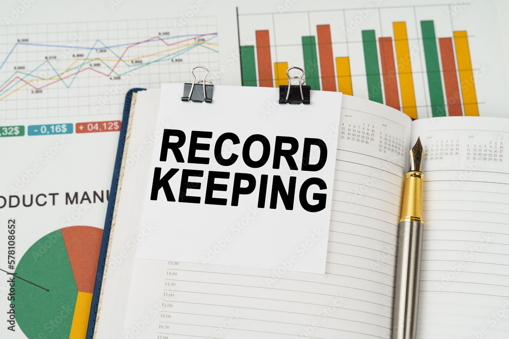 On the business charts is a notepad with the inscription - Record keeping On the business charts is a notepad with the inscription - Record keeping
