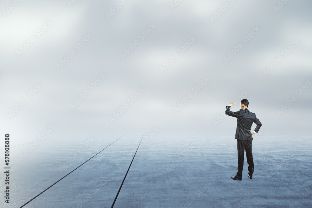 Businessman looking into the distance on abstract dull sky and ground background with mock up place.