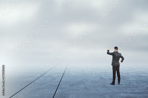 Fotografia Businessman looking into the distance on abstract dull sky and ground background with mock up place