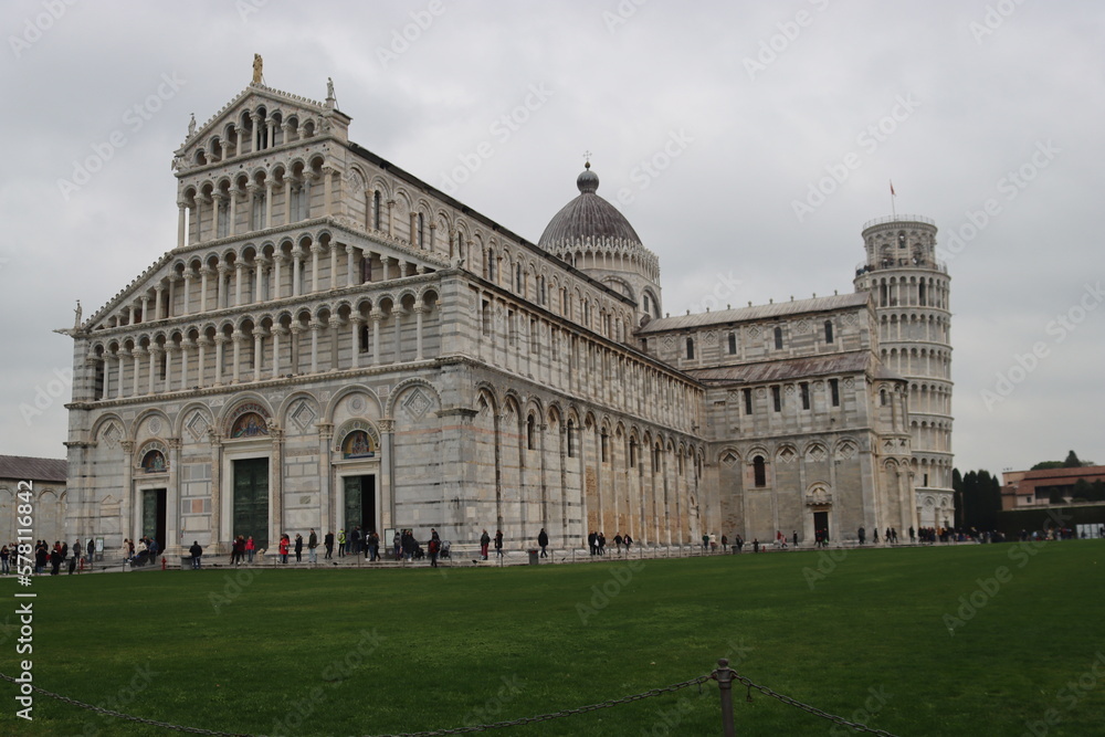 Pisa, Italy - February 25, 2023: Discovering the city of Pisa in winter days. Tower of Pisa with grey sky in the background. Old famous architecutre in Italy.