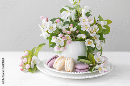 Beautiful composition with delicious French macarons and spring flowers in a white cup. Sweet dessert  early spring white and pink flowers  wedding decor  bride morning