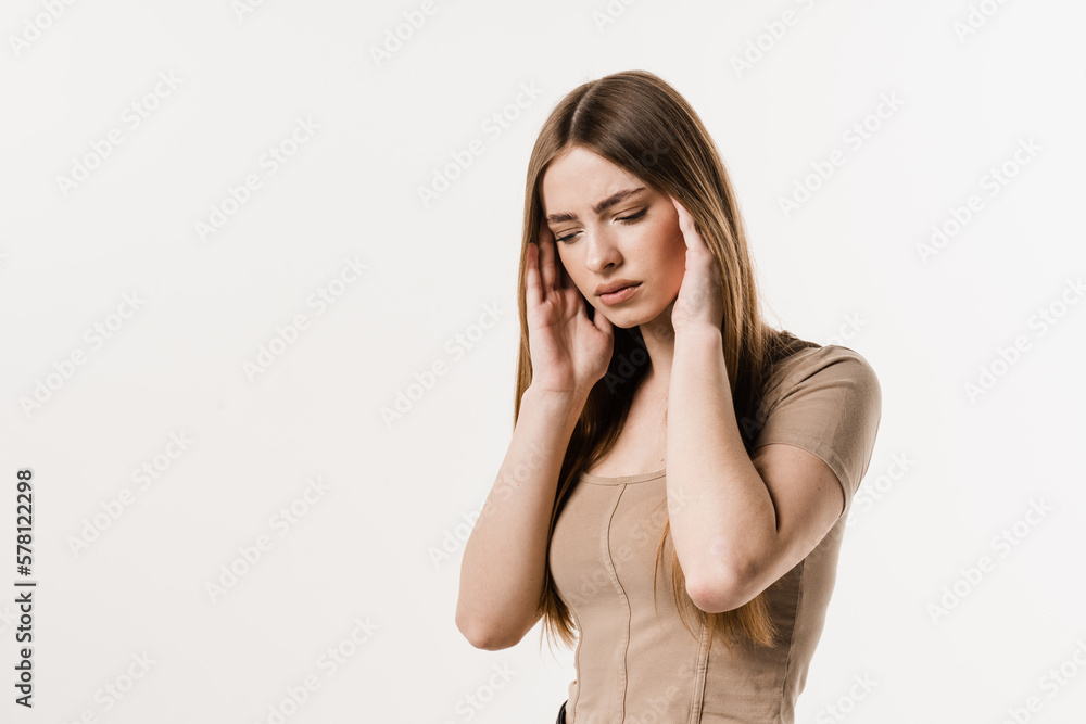 Migraine is a strong headache of girl isolated on white background. Overstressed young woman touches her head because of pain. Depression of attractive girl. Migraine is a strong headache of girl isolated on white background. Overstressed young woman touches her head because of pain. Depression of attractive girl.
