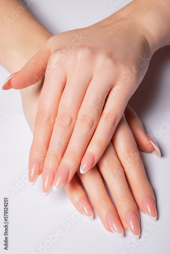 Hands with long nails with french manicure holding seashells