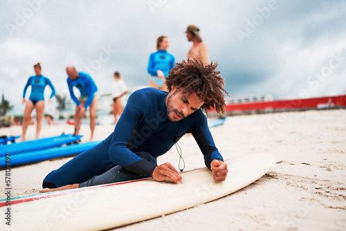 young mixed race male wax the surfboard on the shore of the beach before getting in to surf the waves in Brazil	