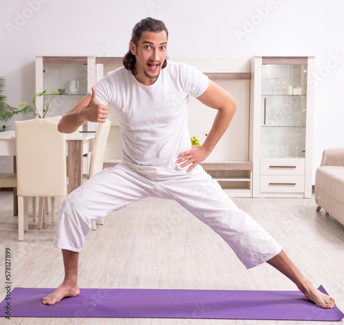 Young man doing physical exercises at home