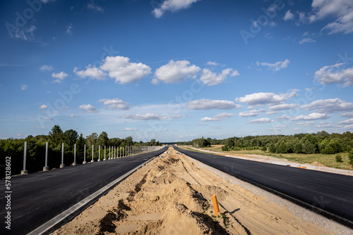 Budowa nowej autostrady. Montaż barier ochronnych i znaków przy nowo budowanej autostradzie. Nowy asfalt.