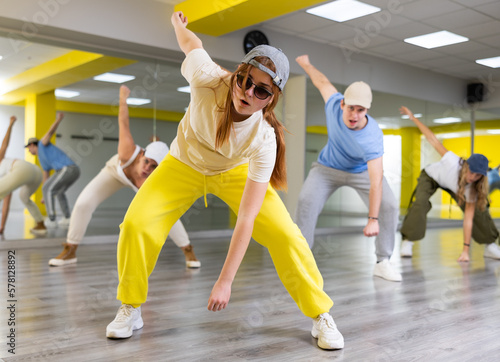Teenager girl in cap dances hip hop dances in dance studio