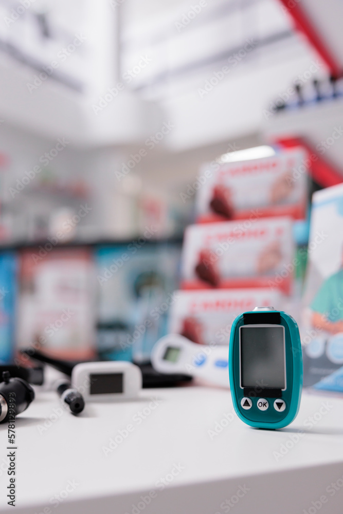 Medical glucometer standing on table ready to measure customers glucose and insulin level in drugstore. Empty pharmacy filled with pharmaceutical products and vitamins. Health care service and concept