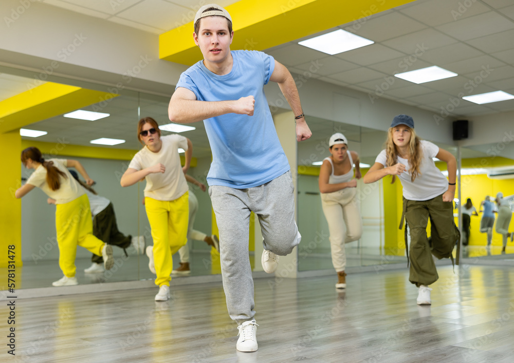 Energetic teenage boy engaging in breakdance in dance studio. Teenagers training Toprock moves