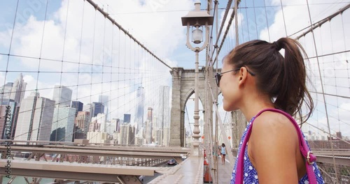 New York City Woman. Beautiful young multicultural woman portrait on Brooklyn bridge, New York city NYC, Manhattan, USA. Smiling tourist in blue dress doing summer travel by landmark. SLOW MOTION photo