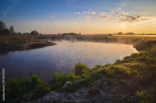 Beautiful morning foggy landscape. Sunrise over the river in Ponidzie in Poland. © shadowmoon30