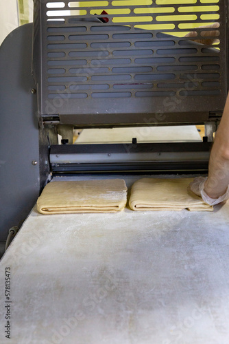 Pastry dough on the table of the press machine. Automation of dough production in the bakery