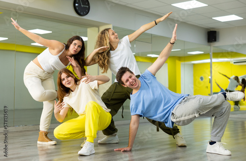 Flexible happy male and female teenage dancers doing elements of breakdance movements and having fun during training in hall