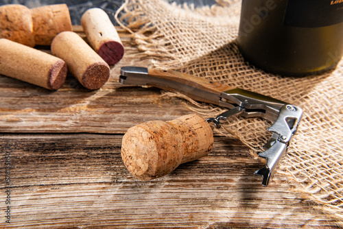 Bottles with wine, corkscrew, and corks on wooden table. Harvest and winemaking concept.