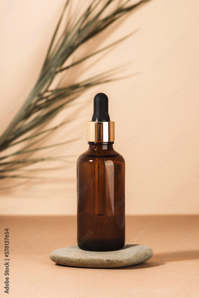 Naklejka premium Brown cosmetic serum bottle on a stone podium. Natural skin care cosmetics concept. Closeup
