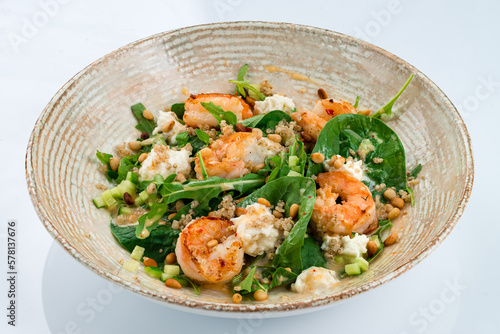 Fresh salad with shrimp, quinoa, arugula, spinach, cucumbers, cream cheese, pine nuts and dressing.