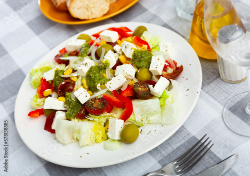Corn, lettuce, pepper, olives, onion, cheese, tomato and pesto sauce served on plate and ready-to-eat.
