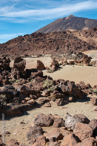 Vertical landscape of volcano el teide with rocks and sand in foregound during sunny summer day in tenerife, spain