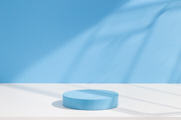 Round blue podium, simple stage and abstract shadows on blue background.