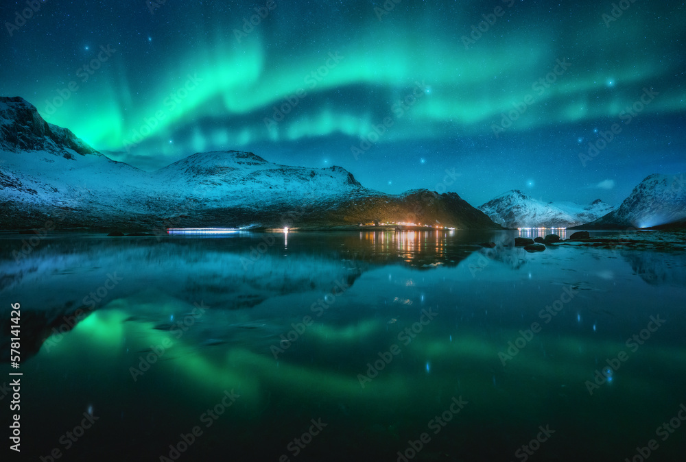Northern lights over the snowy mountains, sea, reflection in water at ...