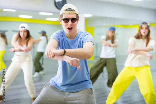 Guy teenager in sunglasses rehearsing modern dances in dance hall