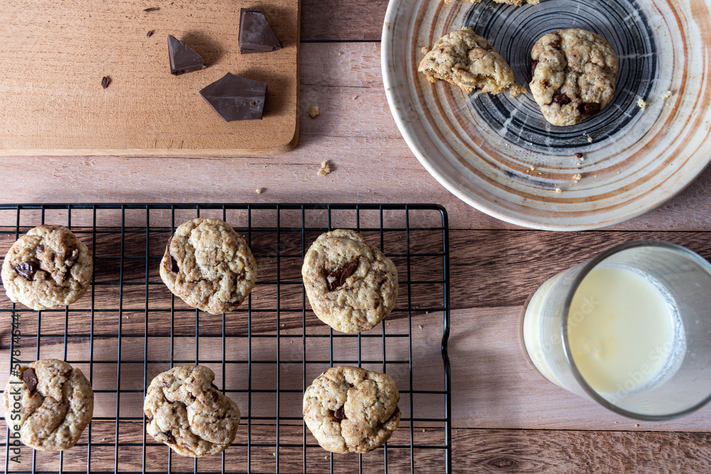 Top view of chocolate chip cookies on a rack and other broken cookies on a plate. Top view of chocolate chip cookies on a rack and other broken cookies on a plate.