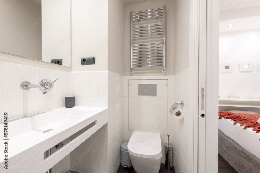 Bathroom with unusually designed sink, chrome taps and heated towel rail, frameless mirror and exit to a bedroom Bathroom with unusually designed sink, chrome taps and heated towel rail, frameless mirror and exit to a bedroom