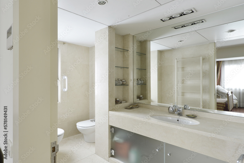 Large luxurious modern style bathroom with a large cream marble countertop with a sink, tempered glass doors and a large built-in mirror on the wall Large luxurious modern style bathroom with a large cream marble countertop with a sink, tempered glass doors and a large built-in mirror on the wall