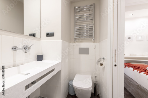 Bathroom with unusually designed sink  chrome taps and heated towel rail  frameless mirror and exit to a bedroom