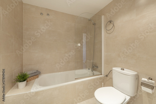 Bathroom with bathtub with folding screen, marble tiling and decorative plants