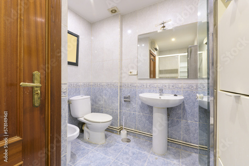 old-fashioned bathroom with frameless mirror on the wall and blue tiles half up to match the floor