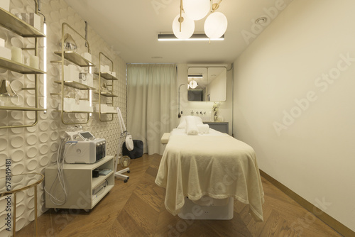Aesthetic treatment room with a relaxation table, creams and appliances to apply massages and cleanings © Toyakisfoto.photos
