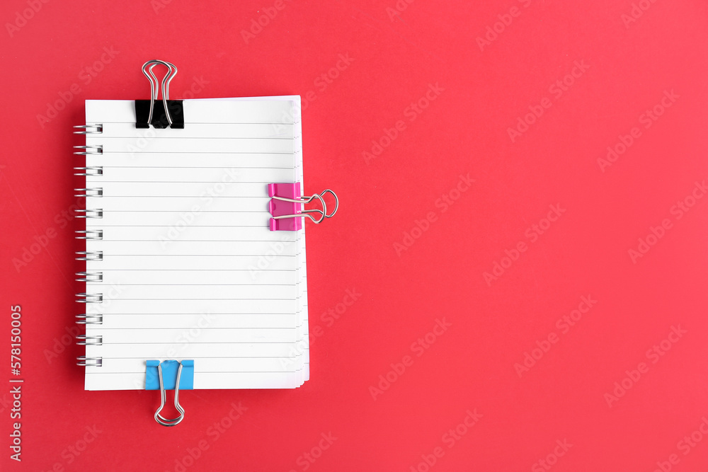 Notebook with binder clips on red background Notebook with binder clips on red background