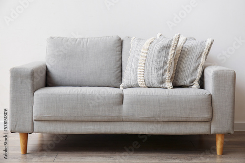 Soft pillows on sofa near light wall